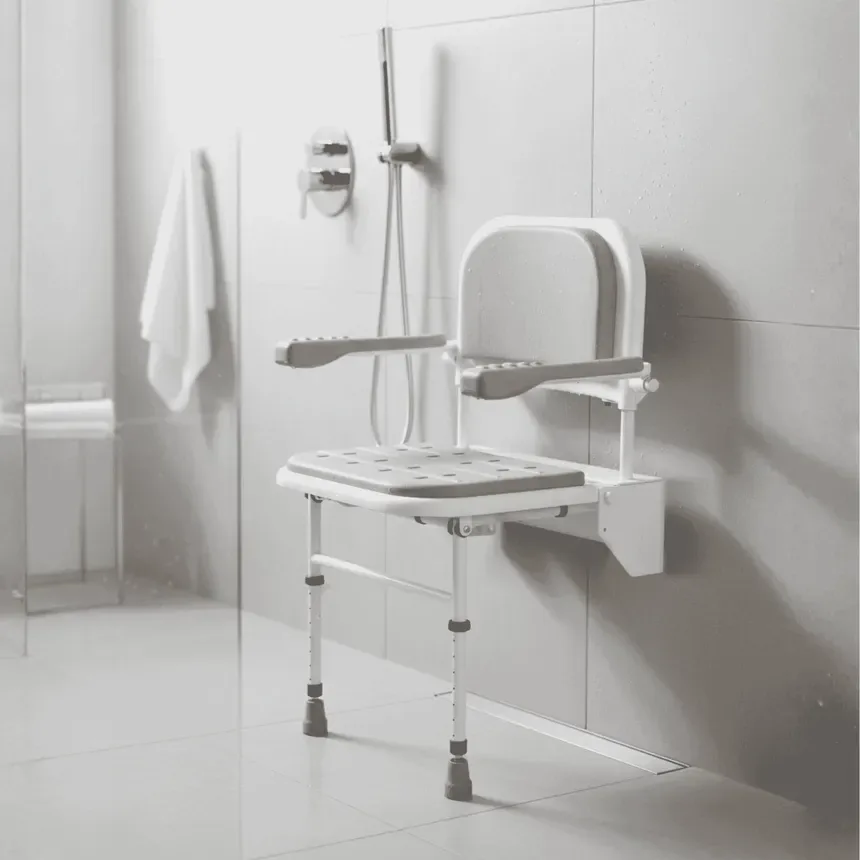 Wall-mounted fold-down shower seat with backrest, arms and support legs, fitted in a tiled wetroom